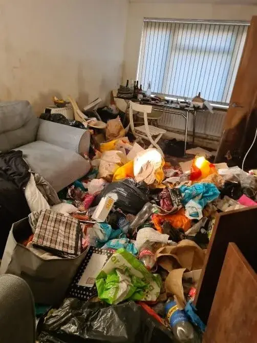 A small room in a domestic property full of furniture and hoarding waste.