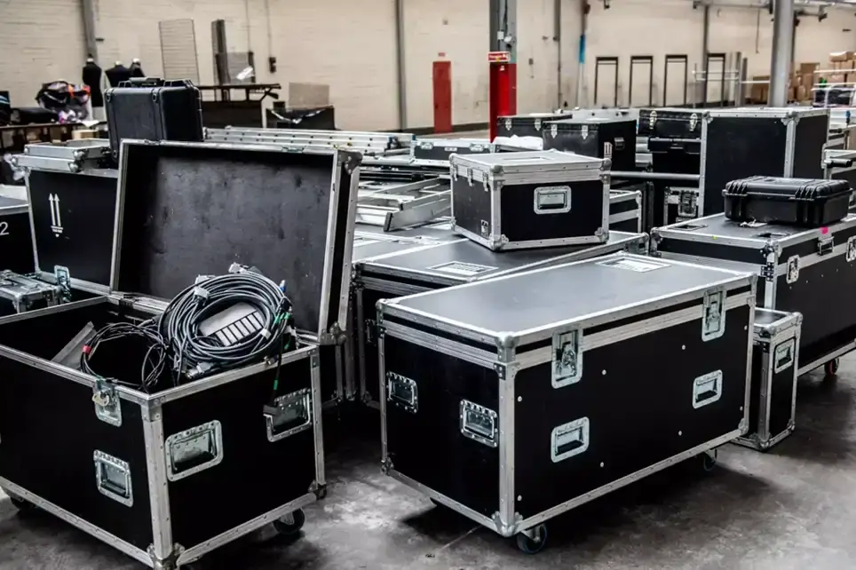 A room full of black flight cases, one is open and full of music equipment.