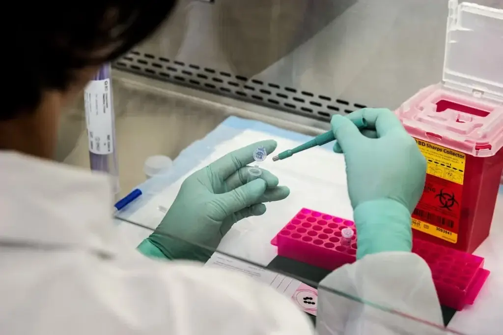 A biohazard sharps disposal bin on a table where a scientist is working.